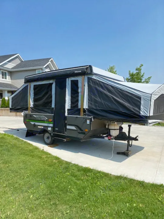 This pop-up camper RV rental is fully extended, parked on a driveway, ready for camping trips under a clear blue sky.. Forest River 1940 LTD 2020