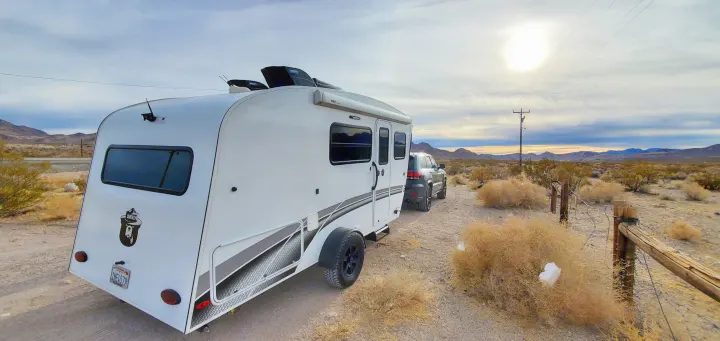 White rv rental travel trailer & SUV exploring a desert landscape. Ideal for serene camping & scenic road trips.. InTech RV Sol Horizon 2020