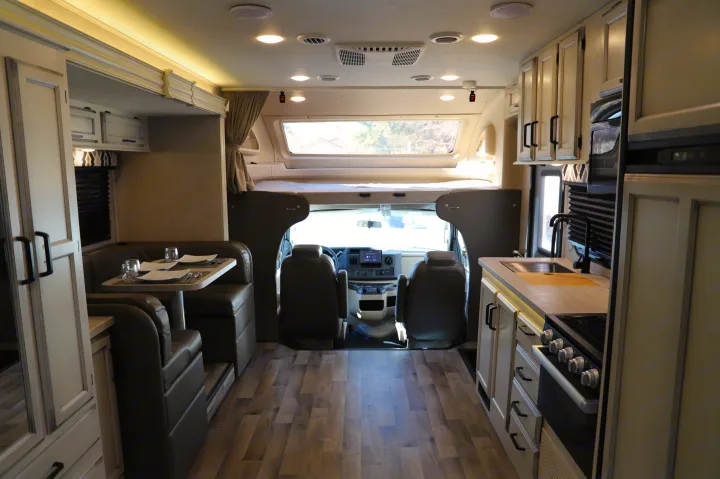 Spacious rv rental interior showing modern kitchen, dining booth, overhead bunk, and front cab area.. Entegra 24B 2022