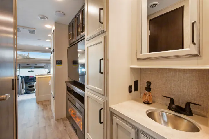 Explore this RV rental's chic interior, showcasing a vanity, sink, integrated TV, and cozy electric fireplace setup.. Other Other 2022
