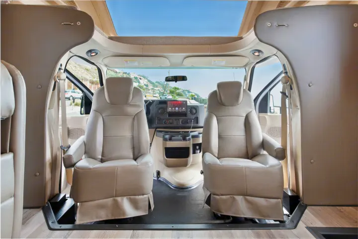 An RV rental's spacious front cabin with comfy driver and passenger seats, a modern dashboard, and an open overhead view.. Other Other 2022