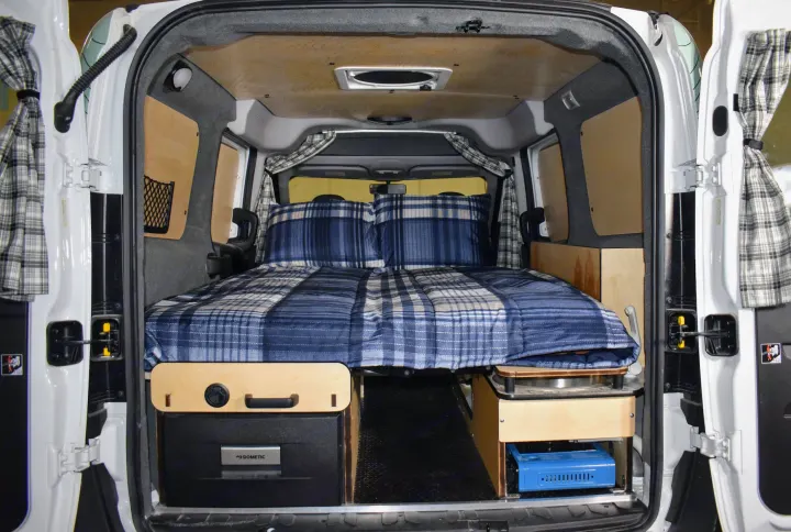 This RV rental boasts a comfortable bed, compact kitchen, and smart storage in its camper van interior.. Dodge Promaster City 2021