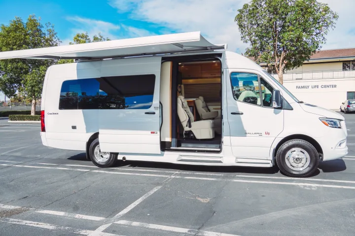 White Coachmen Galleria Li3 camper van parked in a lot, with its side door open to reveal the interior. Awning extended. RV rental.. Forest River Coachmen Galleria 2021