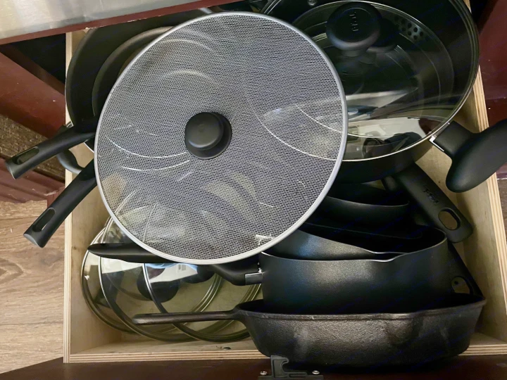 Compact rv rental kitchen drawer: nested pots, pans, lids, and a splatter screen, neatly stored.. Heartland RVs Road Warrior Toy Hauler 2015