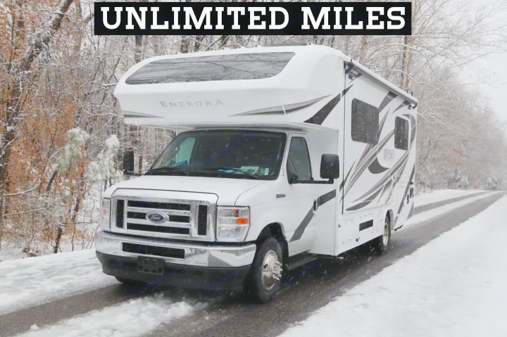 An Entegra Odyssey RV rental is parked on a snow-dusted road amidst snowy trees, offering unlimited winter miles.. Entegra Coach Odyssey 2021