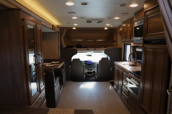 Inside an **rv rental**, featuring a full kitchen right, dining booth left, and front driver's area.. Entegra Coach Odyssey 2021