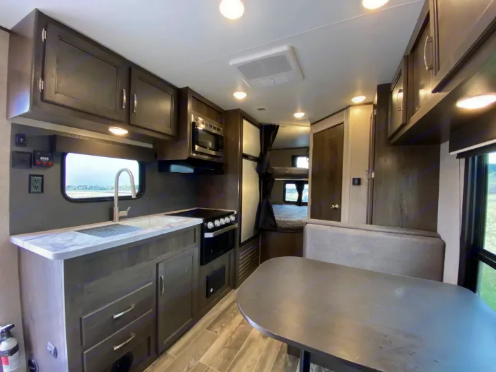 Spacious RV rental interior featuring a full kitchen, dining area, and rear bunk beds, ideal for family trips.. Jayco Jay Flight SLX Baja Edition 2021
