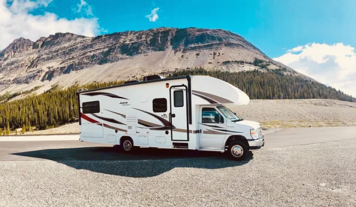 RV rental parked amidst majestic mountains and pine forests, perfect for a scenic road trip and nature exploration.. Jayco Redhawk 2018