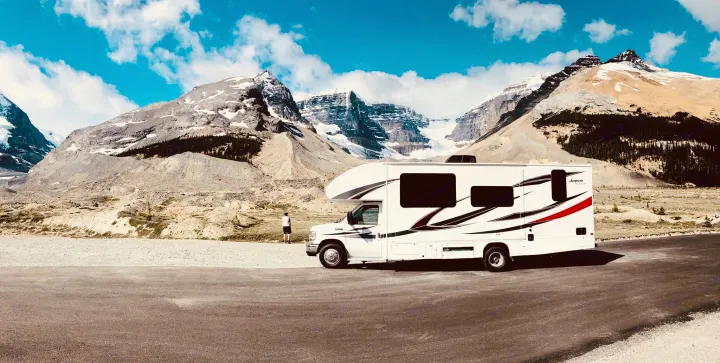 A white RV rental motorhome awaits adventure, parked against majestic snow-capped mountains under a clear blue sky.. Jayco Redhawk 2018