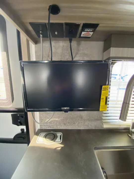 Inside an RV rental: a mounted TV above a kitchen counter with a sink. Ideal for entertainment and meal prep.. Winnebago Micro Minnie 1800BH 2022