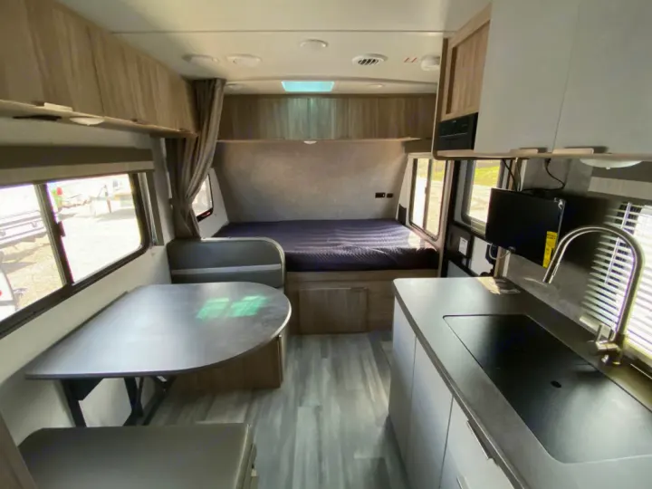 Inside this modern RV rental: a comfortable dinette, compact kitchen, and cozy bed area. Perfect for your next trip.. Winnebago Micro Minnie 1800BH 2022