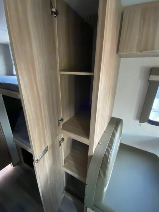 RV rental interior shows a spacious storage cabinet with shelves, bunk beds, and a dinette seat.. Winnebago Micro Minnie 1800BH 2022