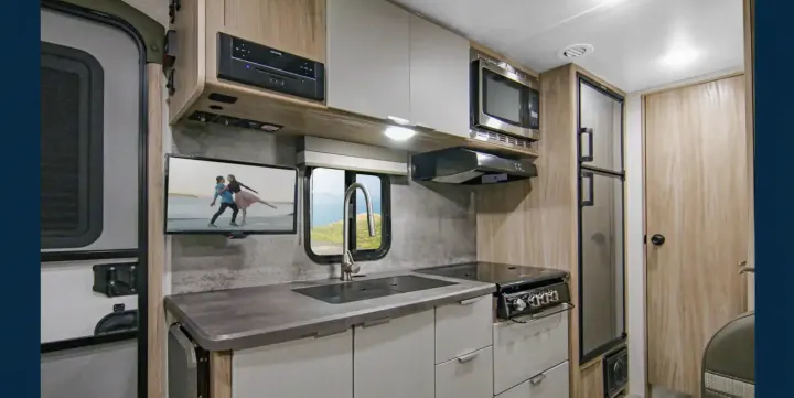 RV rental interior: A modern kitchen with sink, stove, microwave, fridge, TV, and a scenic window view.. Winnebago Micro Minnie 1800BH 2022