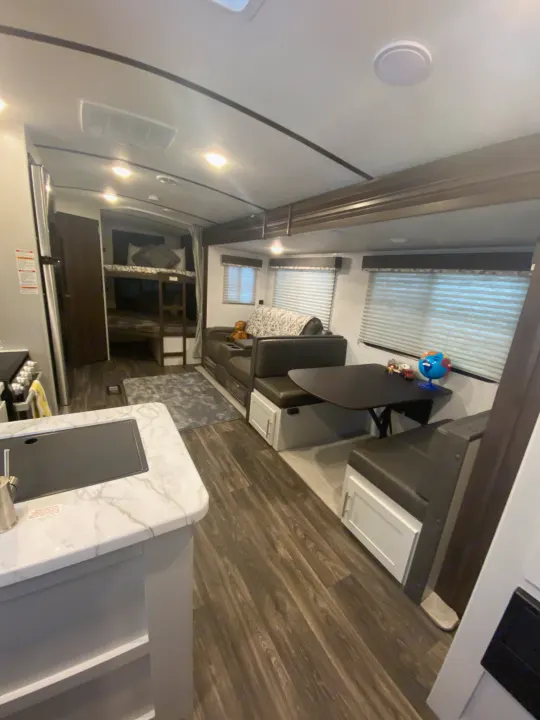 Spacious RV rental interior featuring a modern kitchen, comfortable living/dining area, and convenient bunk beds for family trips.. Keystone RV Bullet Ultra Lite 2021