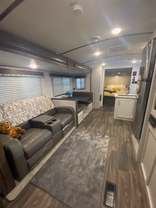Explore this RV rental's cozy interior: leather seating, dining booth, full kitchen, and bedroom.. Keystone RV Bullet Ultra Lite 2021