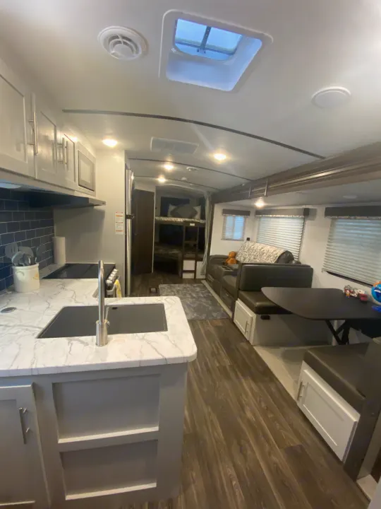 Spacious, modern RV rental interior: a fully-equipped kitchen, comfy living/dining area, and bunk beds.. Keystone RV Bullet Ultra Lite 2021