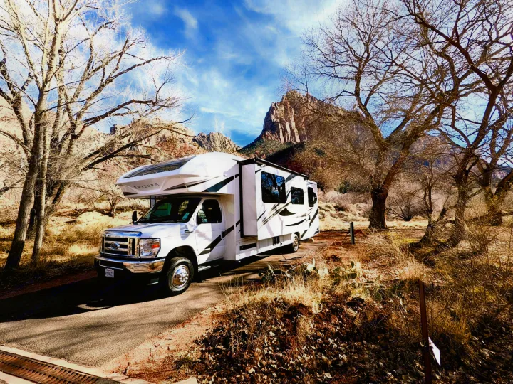 An rv rental Class C motorhome is parked in a scenic campground with beautiful red rock mountains and bare trees.. Other Other 2022