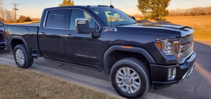 Sleek dark GMC Denali HD truck, perfect for towing your next rv rental adventure. Parked roadside at sunset.. GMC Sierra 2500HD Denali 2020