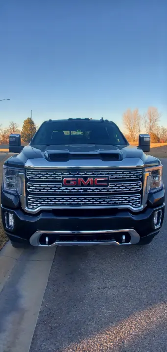 Front view of a robust black GMC pickup truck, ideal for an RV rental trip. Chrome details and large towing mirrors are visible.. GMC Sierra 2500HD Denali 2020