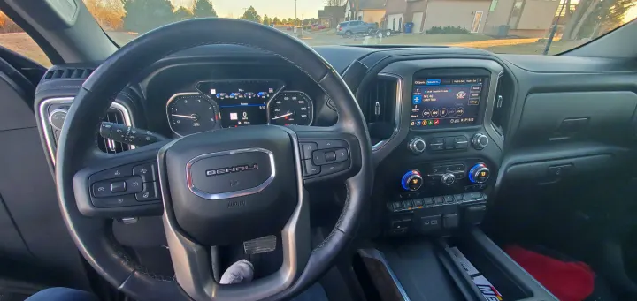 Driver's view inside a GMC Denali, highlighting the steering wheel, digital dashboard, and media display. Ready for any rv rental adventure.. GMC Sierra 2500HD Denali 2020