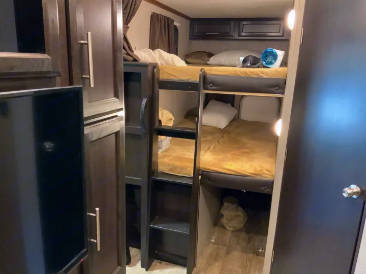 Inside this modern RV rental, find a comfortable bunk bed setup with two beds, integrated storage, and a private door. Ideal for travel.. Jayco Eagle HT 2019