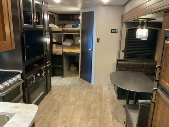 Inside a modern RV rental: kitchen, entertainment with TV/fireplace, bunk beds, and dining booth. Cozy and functional.. Jayco Eagle HT 2019