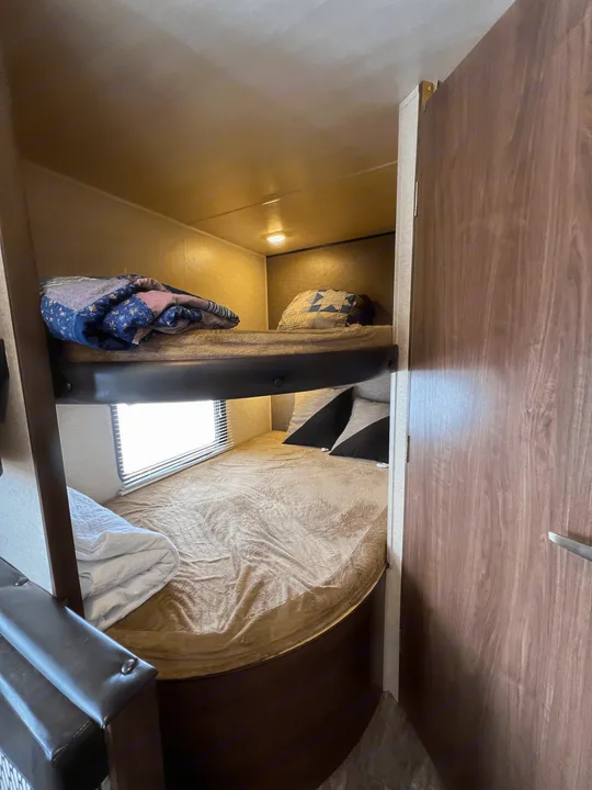 RV rental bunk beds: upper bed with quilt, lower with pillows, and window for cozy sleeping.. Heartland RVs Trail Runner SLE 2017