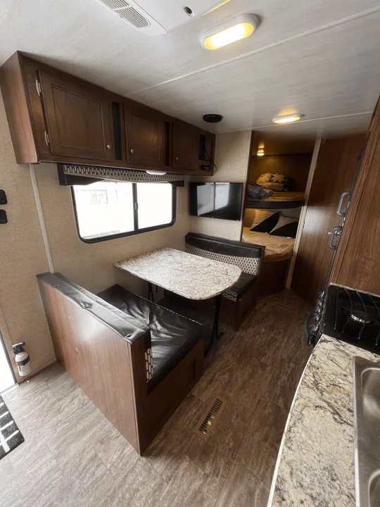 Step inside this RV rental! Features a dinette, kitchen, bunk beds, & warm wood tones for comfortable travel.. Heartland RVs Trail Runner SLE 2017