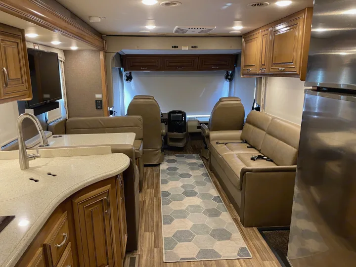 An inviting RV rental interior, showing the kitchen counter, comfortable lounge seating, and cockpit. Ready for your next adventure.. Thor Palazzo 2019