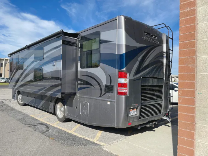 A large grey motorhome, ideal for an rv rental, showcasing an extended slide-out, wavy graphics, and a rear ladder.. Thor Palazzo 2019