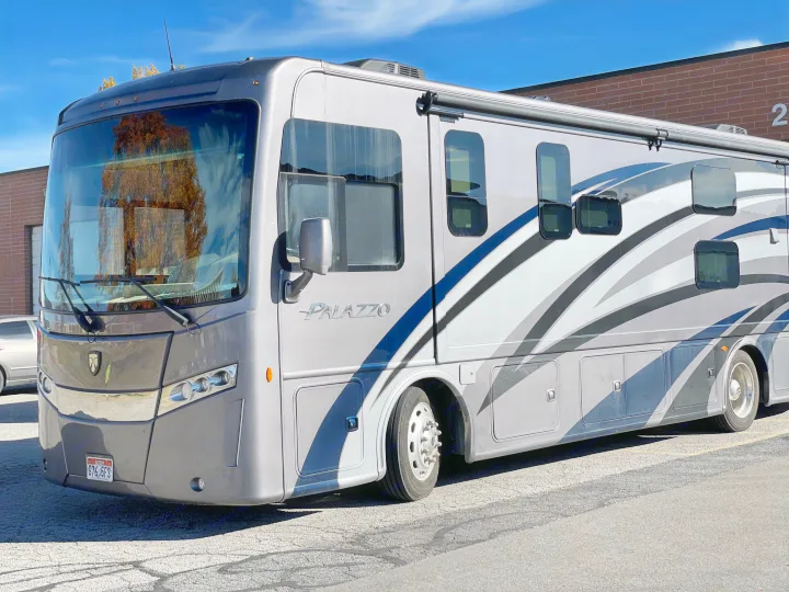 A sleek gray Thor Palazzo RV, ideal for an rv rental, is parked outdoors. Its modern design suggests adventure awaits.. Thor Palazzo 2019