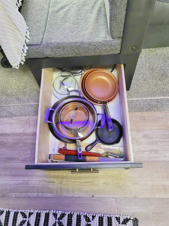 RV rental kitchen drawer stocked with copper pots, cast iron pan, & cooking utensils for travel convenience.. Forest River Cherokee 2021