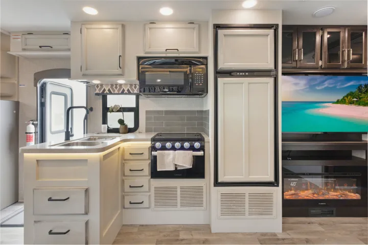 Spacious RV rental kitchen with modern appliances, sink, oven, and fridge, plus a TV and fireplace.. Other Other 2022