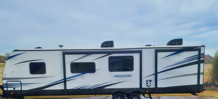 Modern white travel trailer, an ideal RV rental, showcasing blue and black accents and roof vents. Ready for your next adventure.. Cruiser RV Embrace Ultra Lite 2019