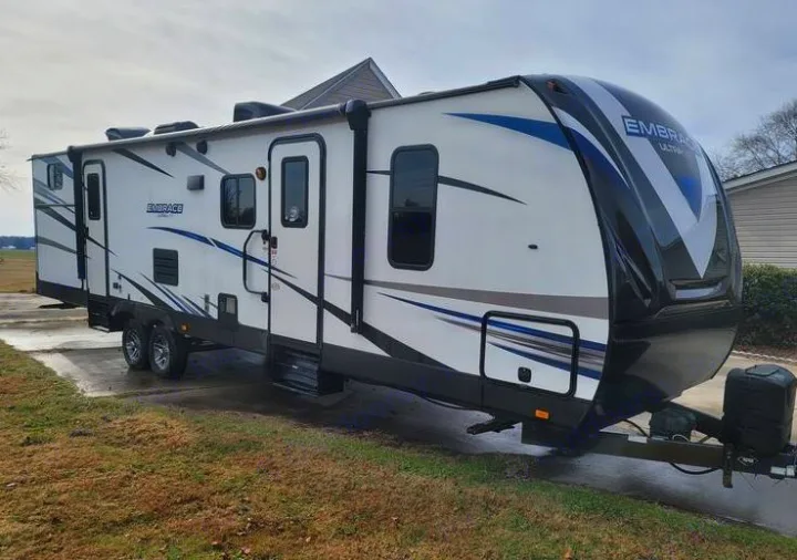 Embrace travel trailer RV rental. This white RV with blue and black accents is parked on a paved driveway, ready for adventure.. Cruiser RV Embrace Ultra Lite 2019