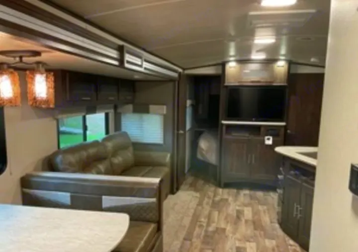 Inside this RV rental: a spacious living area with sofa and dinette, entertainment center, kitchen, and bedroom access.. Cruiser RV Embrace Ultra Lite 2019