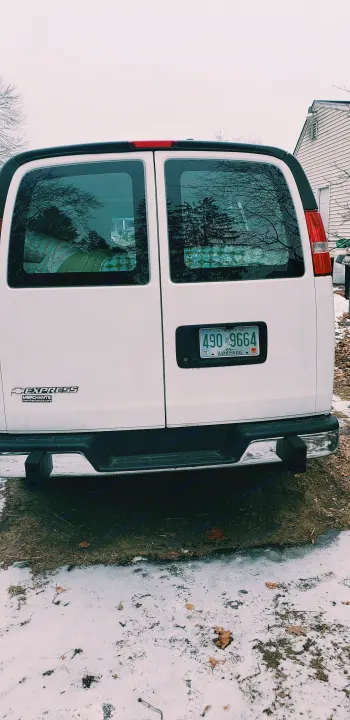 Rear of a white Chevy Express van, a versatile RV rental option, parked on snowy ground with a New Hampshire plate.. Chevrolet Express 2018