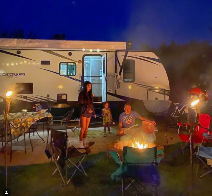 RV rental camping at night! Family enjoying s'mores by a campfire beside their illuminated RV.. Cruiser RV Embrace Ultra Lite 2019