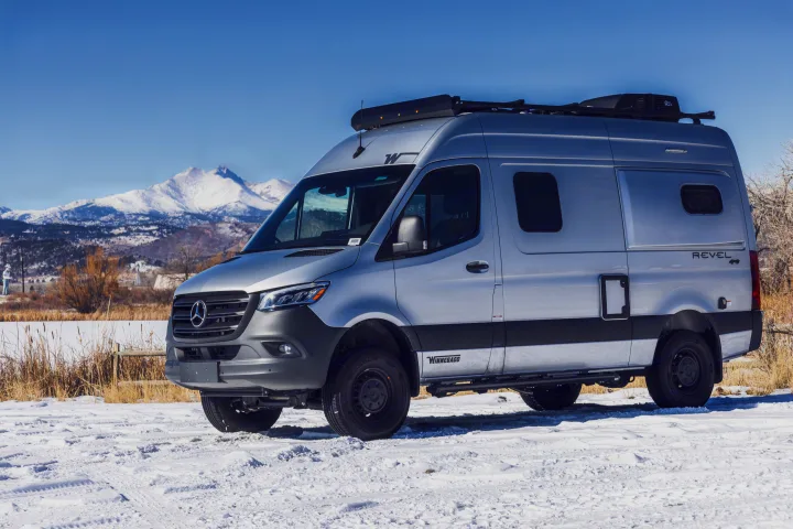 Silver Winnebago Revel 4x4 camper van rv rental parked on snow with mountains in background.. Winnebago Revel 2022