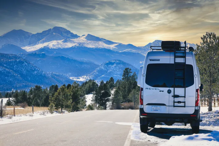 A Winnebago Revel rv rental is parked roadside with stunning snow-capped mountains. Ideal for a winter adventure!. Winnebago Revel 2022
