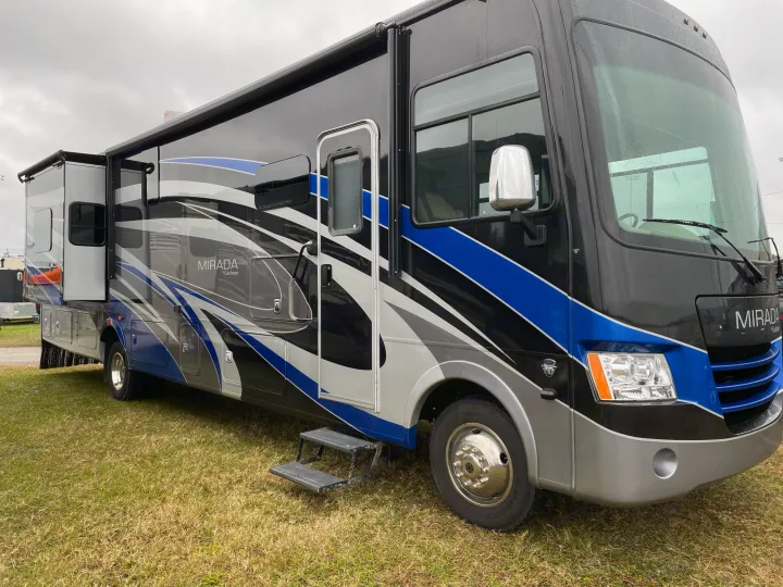 Explore the open road! This large black, blue, and gray Mirada motorhome is a prime RV rental option, parked on grass.. Coachmen Mirada 2018