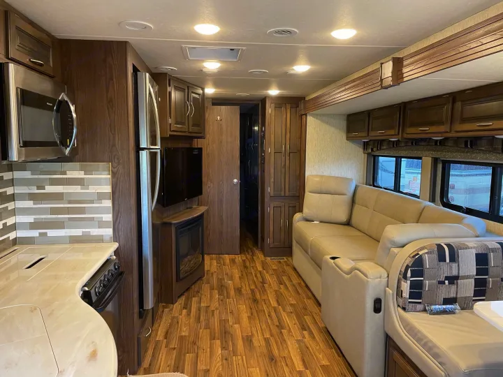 Explore this bright rv rental interior, featuring a full kitchen, comfy sofa, fireplace, and ample storage for your journey.. Coachmen Mirada 2018