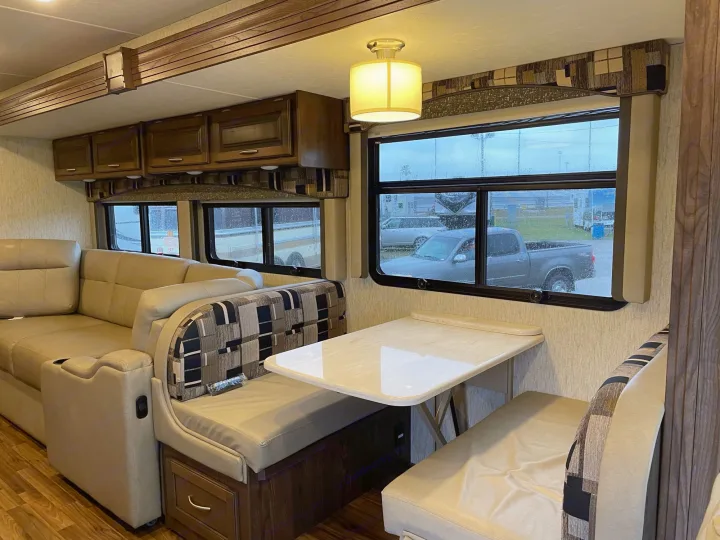 Spacious RV rental interior featuring a comfy sofa, dinette table, and ample windows for bright views.. Coachmen Mirada 2018