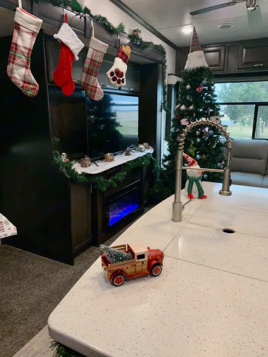 Cozy RV rental holiday decor: Christmas stockings, gnome tree, mini village, and festive truck create a warm interior.. Heartland Elkridge 2019