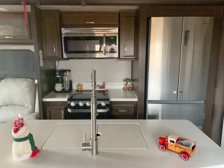 This RV rental features a modern kitchen with stainless steel appliances, dark cabinets, and festive holiday decor.. Heartland Elkridge 2019