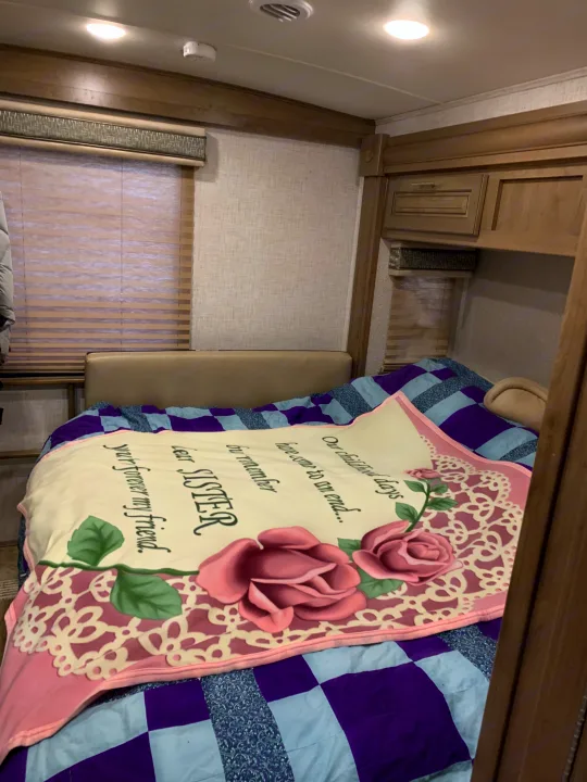 Cozy RV rental bedroom featuring a "Sister" blanket on a bed with a blue and purple quilt.. Forest River Georgetown 2019