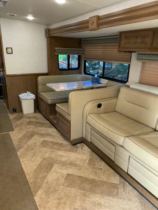 Bright RV rental interior showcasing a spacious dinette area and a large, inviting sofa. Ideal for your next motorhome adventure!. Forest River Georgetown 2019