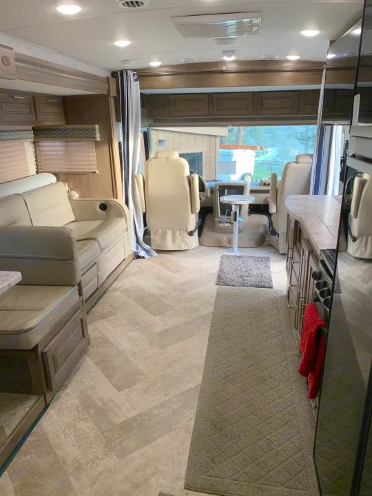 RV rental interior: A bright, modern living space with light flooring, sofa, kitchen, and front cockpit seats.. Forest River Georgetown 2019