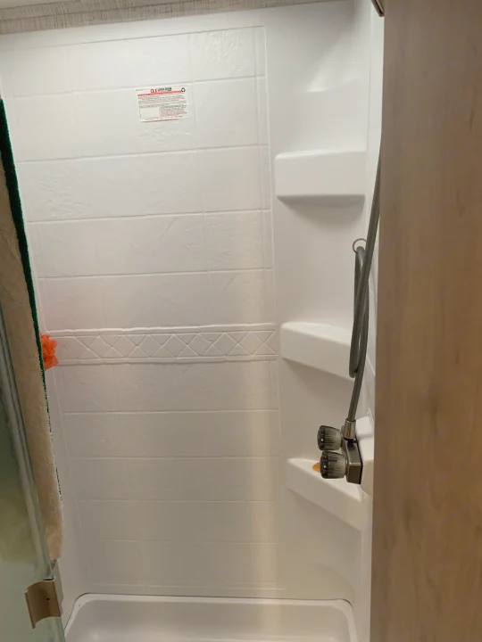 RV rental shower interior: white walls with tile pattern, visible shower head, and glass door.. Forest River Georgetown 2019