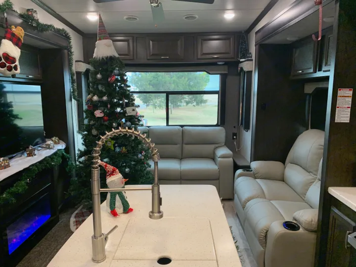 An RV rental's cozy living area with festive Christmas decorations, including a tree, snowman, & comfy recliners.. Heartland RVs Elkridge 2019